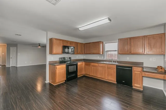 a kitchen with granite countertop wooden floors and white stainless steel appliances
