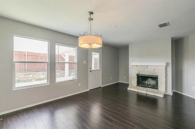 a view of an empty room with wooden floor fireplace and a window