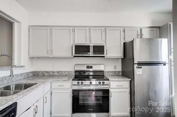 a kitchen with white cabinets and stainless steel appliances