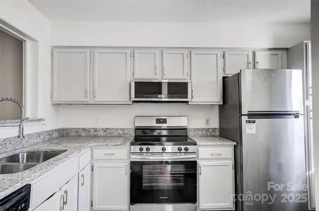 a kitchen with white cabinets and stainless steel appliances
