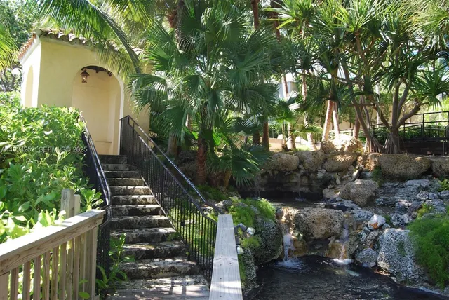 a view of a yard with plants and large trees