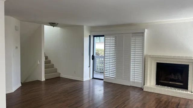 an empty room with wooden floor fireplace and windows