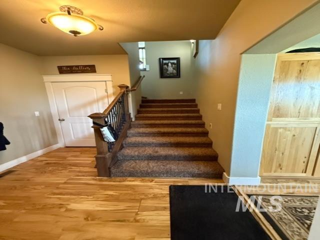 1520 Scheloske Road Weiser, ID 83672 - Photo 26 of 42 Staircase with wood newel post and wrought iron balusters, featuring carpeted treads and risers
