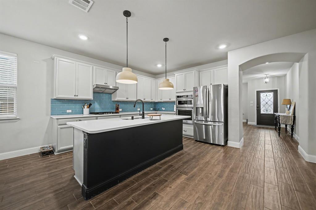 433 Forestridge Drive Fate, TX 75087 - Photo 13 of 38 a large kitchen with stainless steel appliances kitchen island granite countertop a large center island attached withe living room