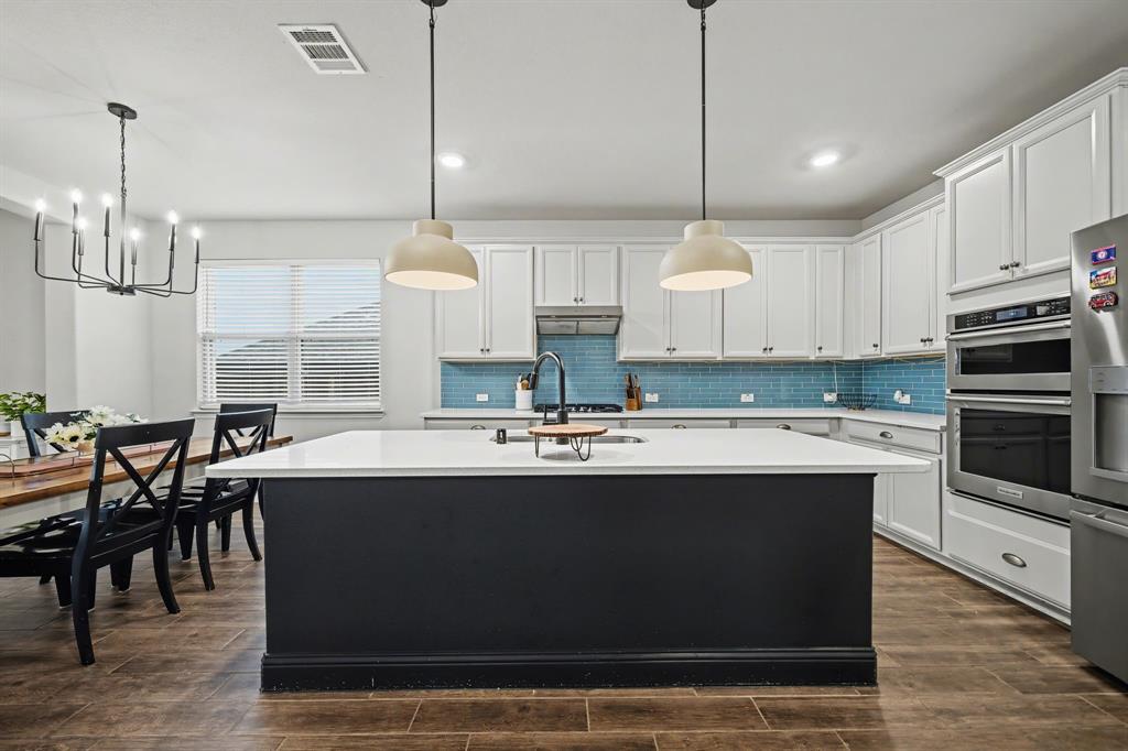 433 Forestridge Drive Fate, TX 75087 - Photo 14 of 38 a kitchen with kitchen island granite countertop a sink a counter top space appliances and cabinets