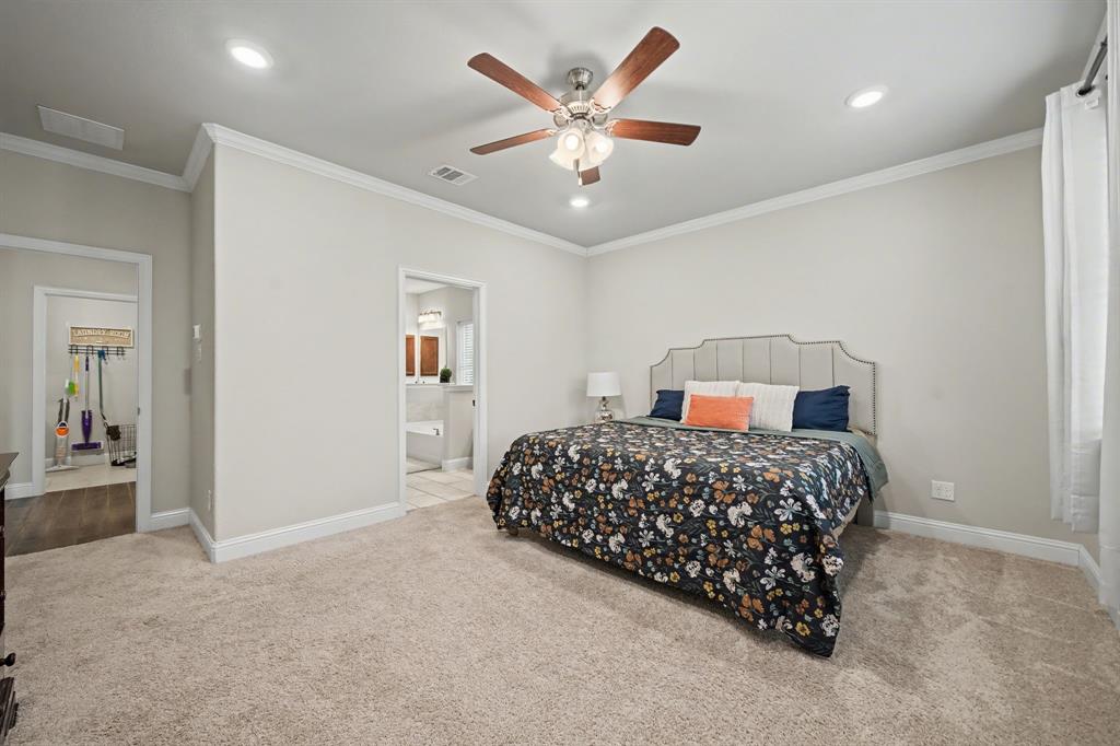 433 Forestridge Drive Fate, TX 75087 - Photo 19 of 38 a bedroom with a large bed and a chandelier