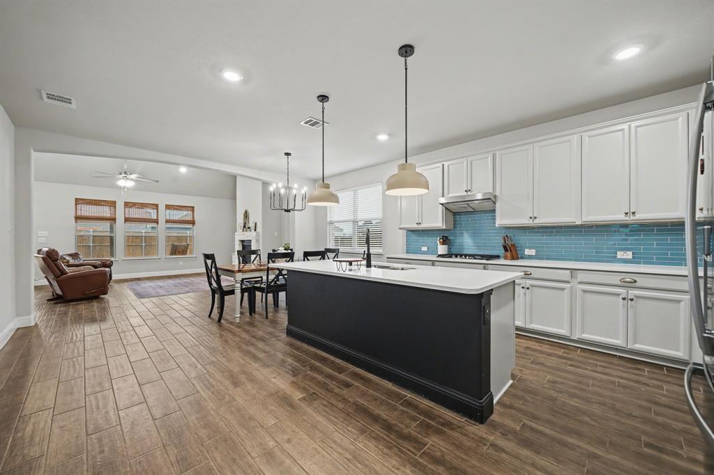 433 Forestridge Drive Fate, TX 75087 - Photo 7 of 38 a kitchen with stainless steel appliances granite countertop a stove a sink dishwasher a refrigerator and white cabinets with wooden floor