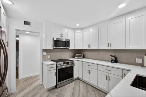 a kitchen with white cabinets stainless steel appliances and sink