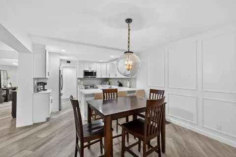 a dining room with furniture a chandelier and kitchen view