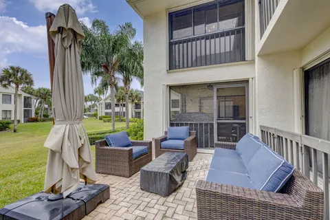 a view of a patio with couches chairs and a table and chairs with wooden floor and fence