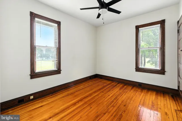 a view of an empty room with window and wooden floor