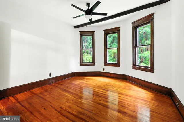 a view of an empty room with a window and wooden floor