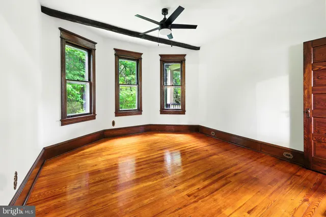 a view of an empty room with window and chandelier fan