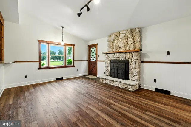 an empty room with windows fireplace and wooden floor