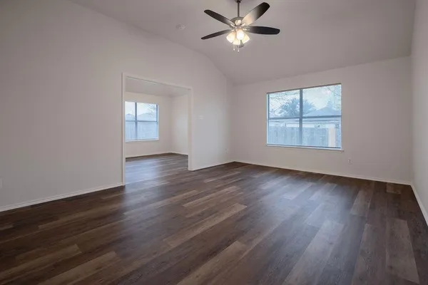 an empty room with wooden floor and windows
