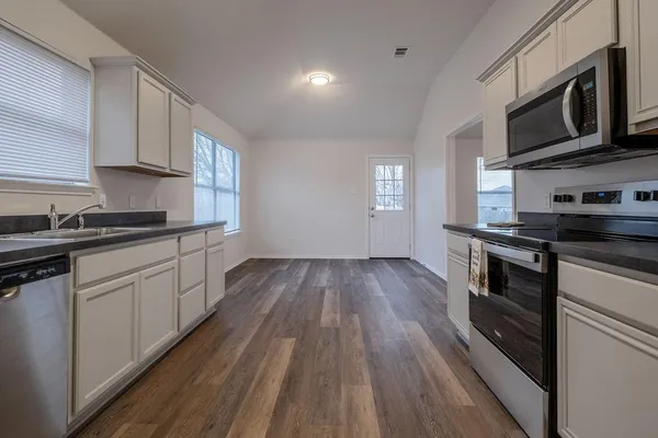 a view of a kitchen with wooden floor and a window