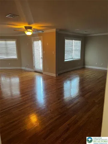 an empty room with wooden floor cabinet and windows