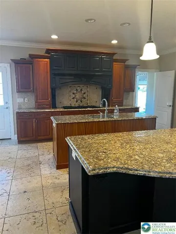 a kitchen with kitchen island granite countertop a stove a sink dishwasher and cabinets