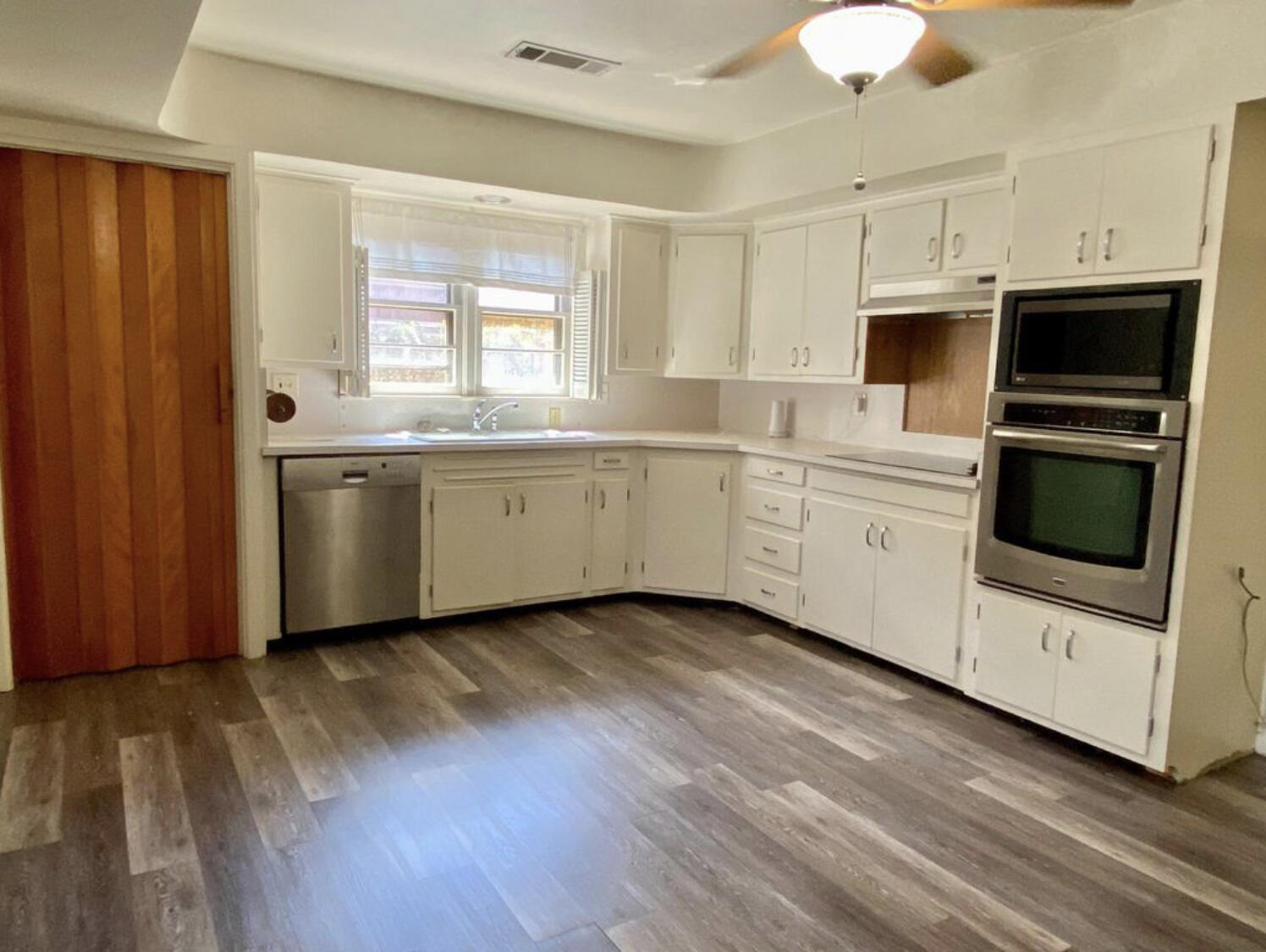 3505 46th Street Lubbock, TX 79413 - Photo 7 of 9 a kitchen with stainless steel appliances a stove a sink and white cabinets with wooden floor