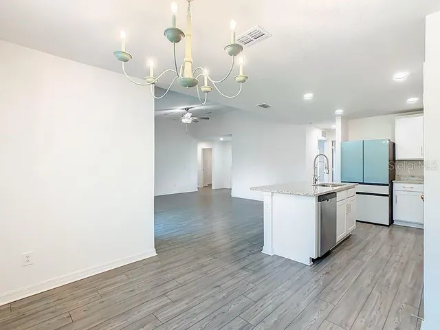 a view of a kitchen with kitchen island a sink wooden floor and stainless steel appliances