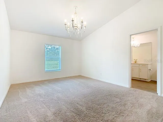 an empty room with a chandelier and a ceiling fan
