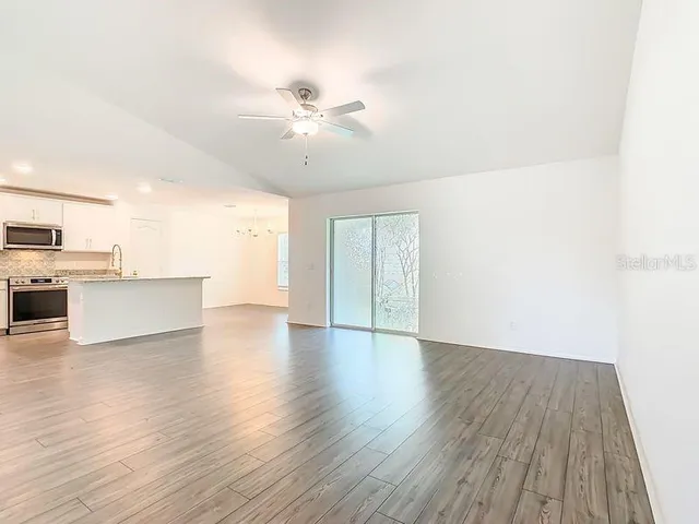 a view of a kitchen with wooden floor and ceiling fan