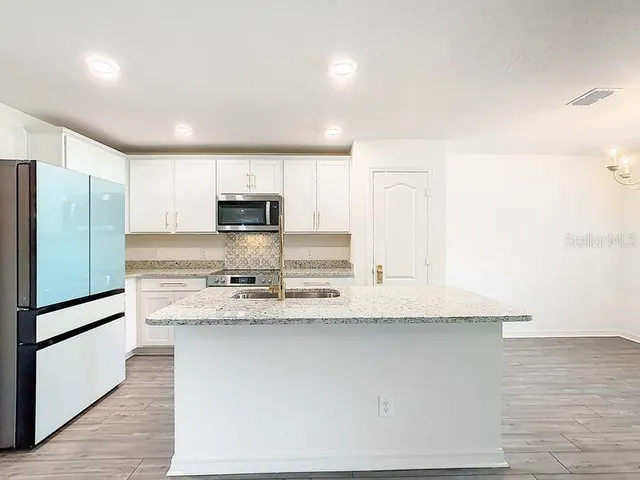 a kitchen with stainless steel appliances granite countertop a refrigerator a stove and a sink