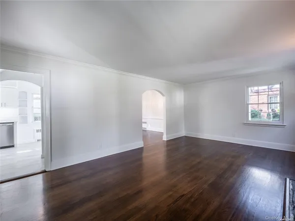 a view of a hallway with wooden floor and a kitchen