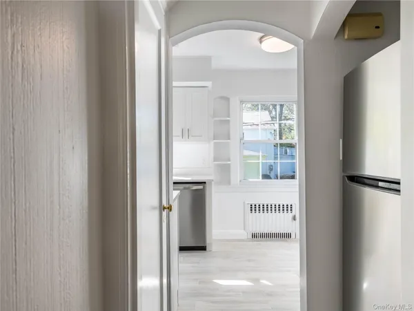 a kitchen with stainless steel appliances granite countertop a stove a sink a refrigerator and white cabinets with wooden floor