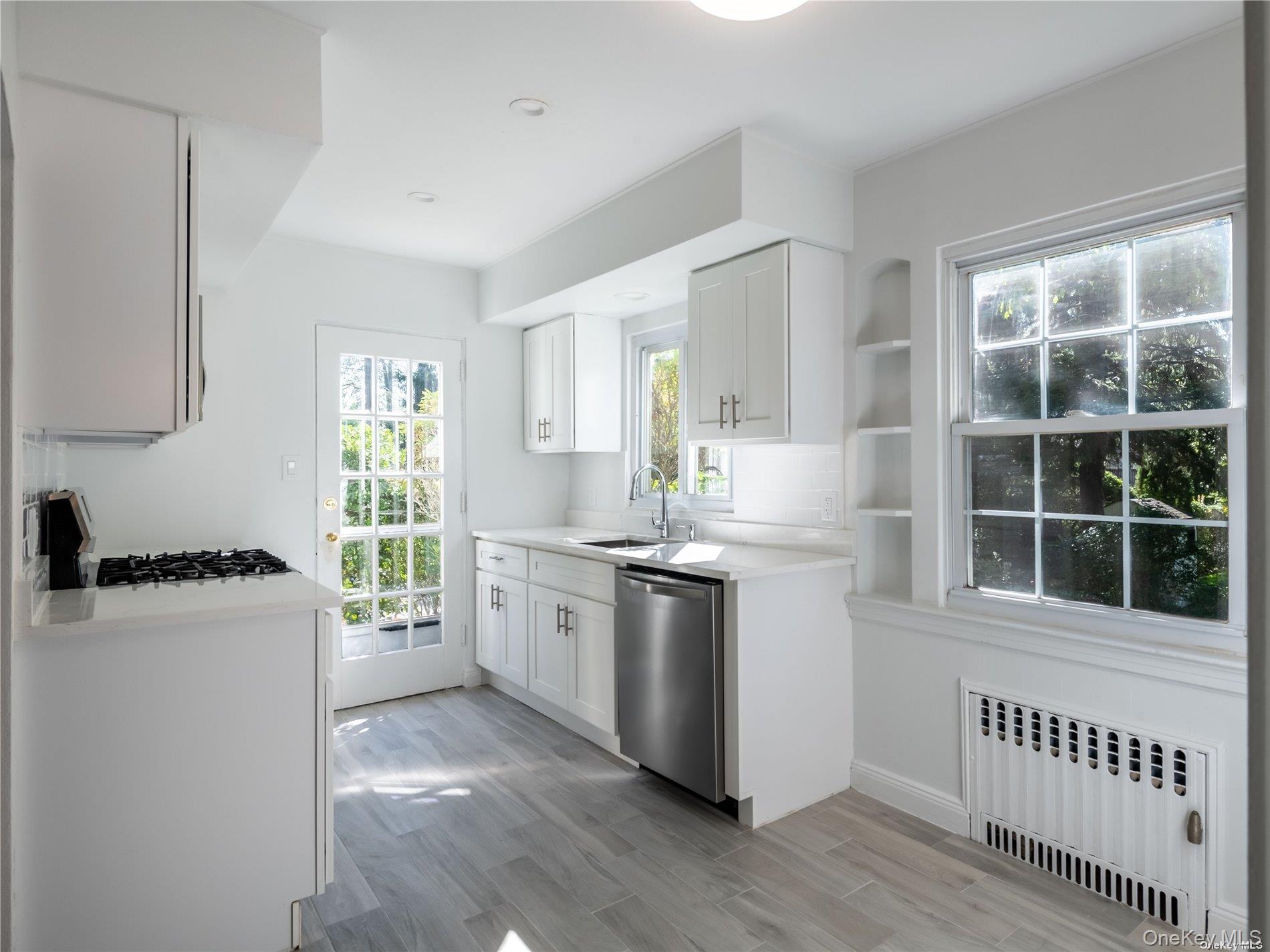 109 Chase Road Manhasset, NY 11030 - Photo 13 of 28 a kitchen with stainless steel appliances granite countertop a stove a sink a refrigerator and white cabinets with wooden floor