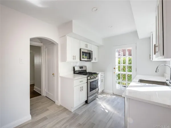 a kitchen with granite countertop a sink wooden floor and stainless steel appliances