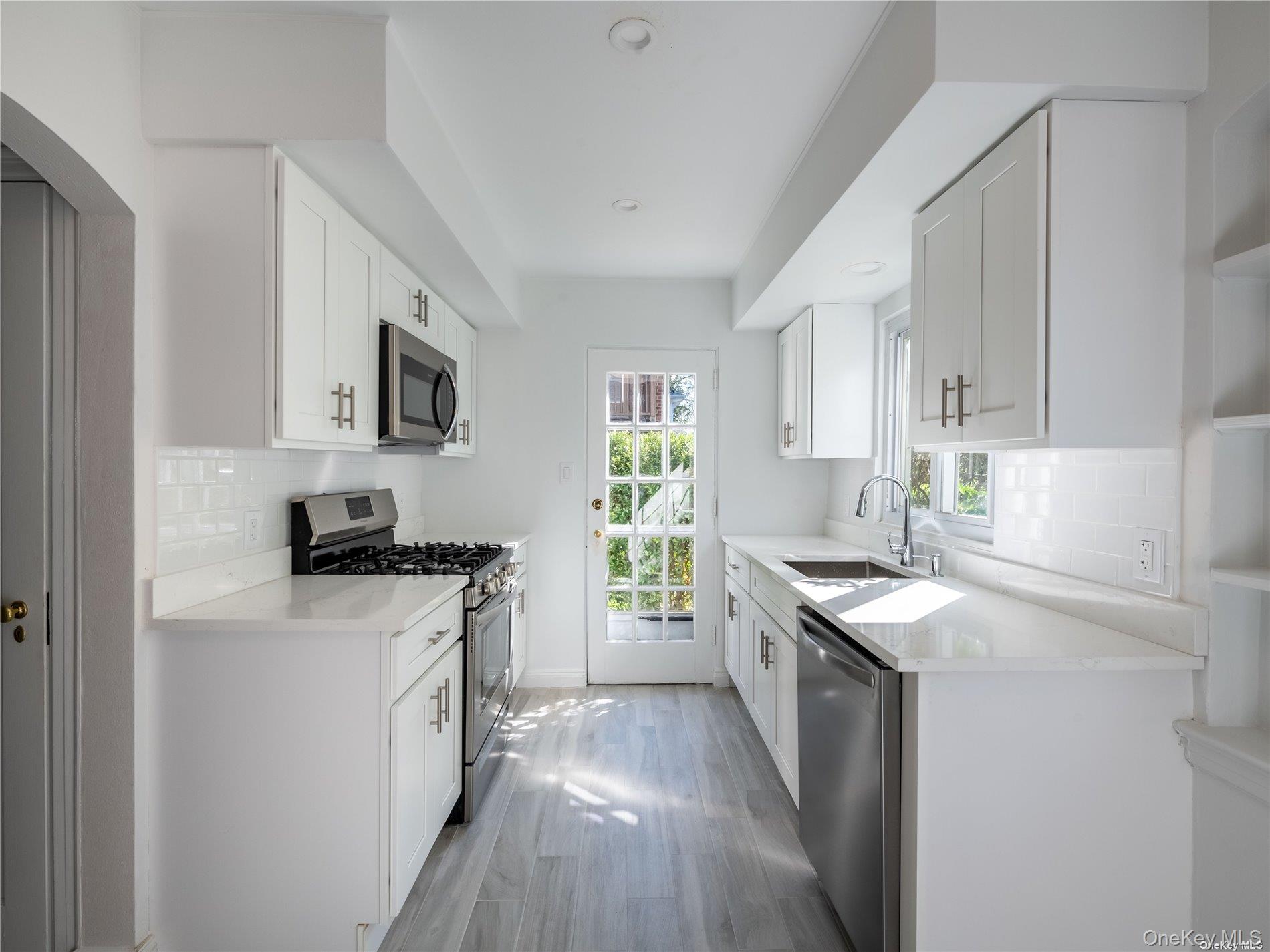109 Chase Road Manhasset, NY 11030 - Photo 15 of 28 a kitchen with granite countertop a sink wooden floor and stainless steel appliances