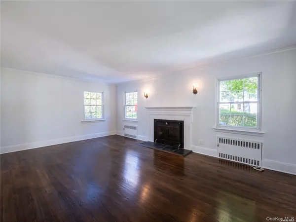 an empty room with wooden floor a fireplace and windows