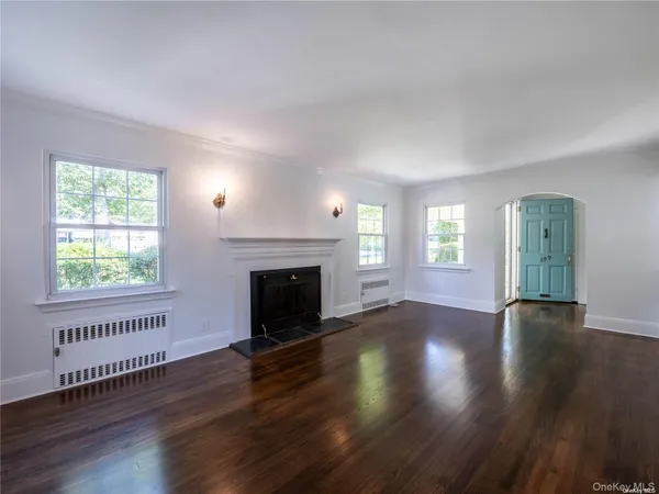 an empty room with wooden floor fireplace and windows