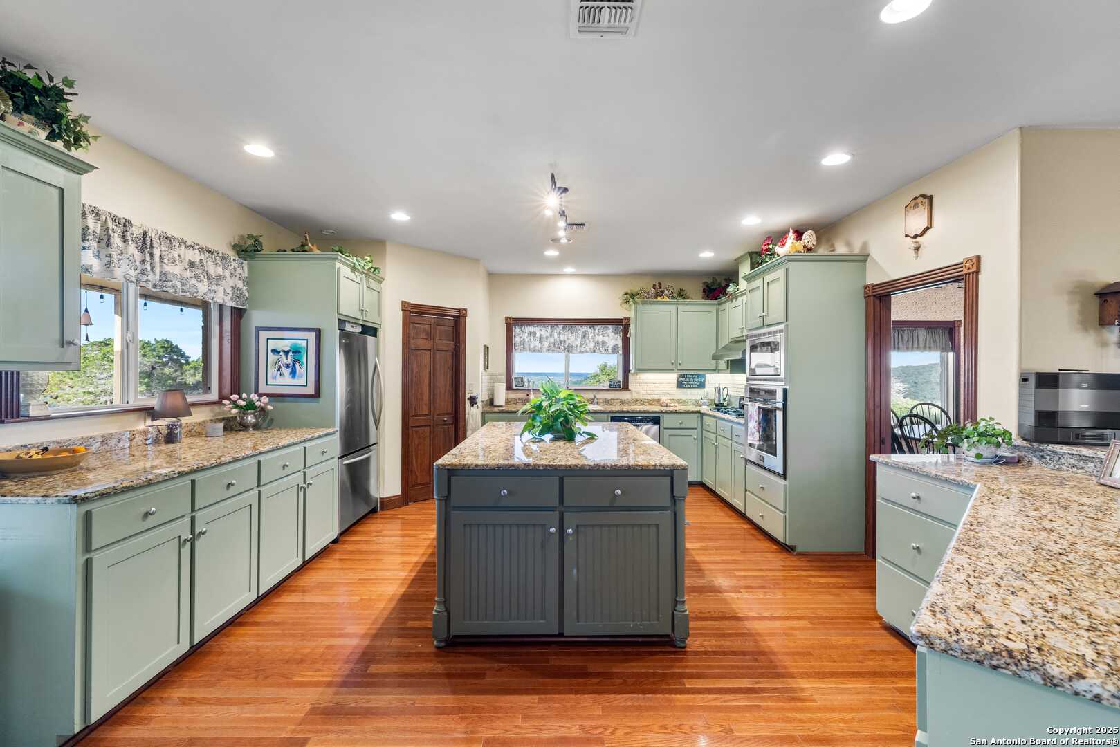 247 Huntleigh Road South Ingram, TX 78025 - Photo 8 of 41 a large kitchen with stainless steel appliances kitchen island granite countertop a large kitchen island a stove a refrigerator a sink dishwasher and wooden cabinets with wooden floor