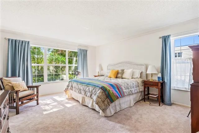 a bed sitting in a spacious bedroom next to a window