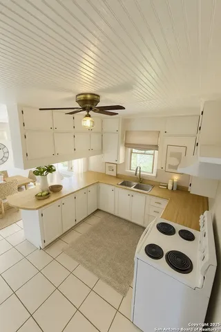 a kitchen with a sink a stove and white cabinets
