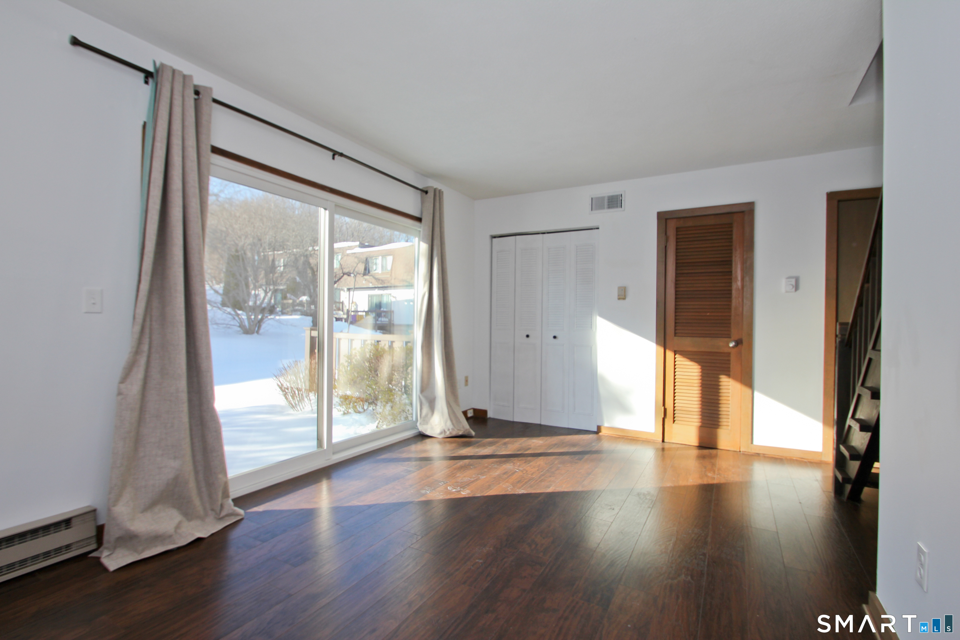 a view of an empty room with wooden floor and a window
