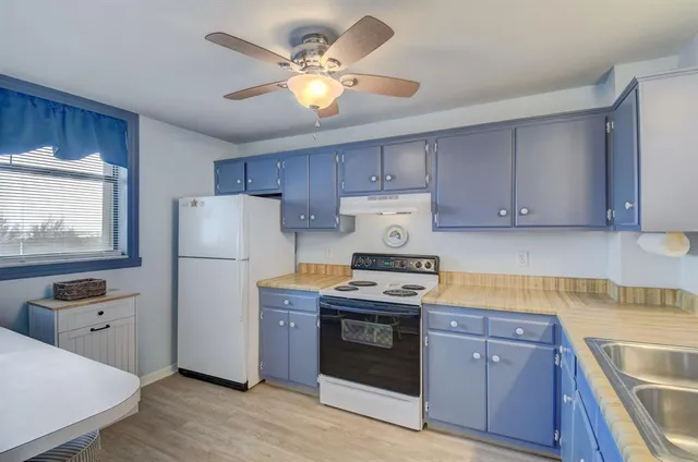 a kitchen with a stove a refrigerator and a sink with wooden cabinets