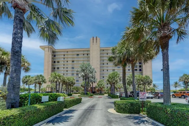 a front view of multi story residential apartment building with yard and green space