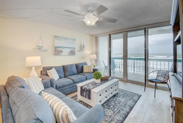 a living room with furniture and a large window with balcony view
