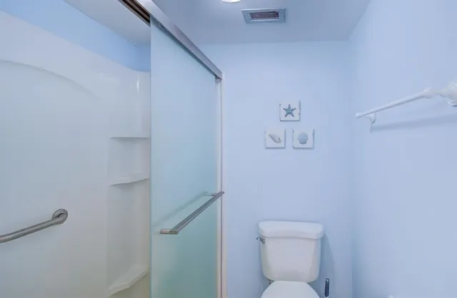 a white toilet sitting next to a shower
