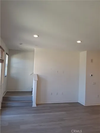 a view of an empty room with wooden floor and stairs