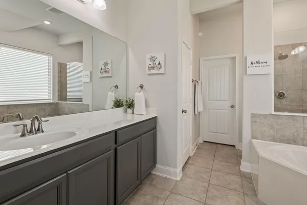 a spacious bathroom with a granite countertop sink a mirror a bathtub and shower