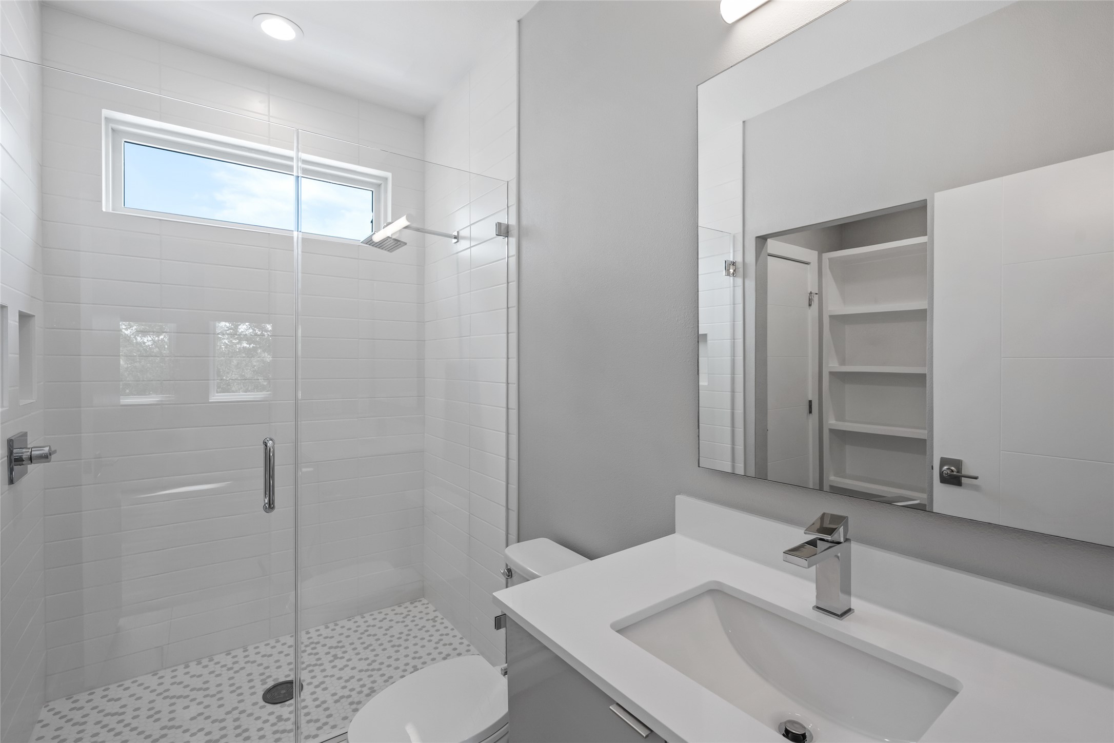 2108 Tillery Street, Unit 16 Austin, TX 78723 - Photo 12 of 15 Contemporary bathroom featuring a glass-enclosed shower with a transom window, wall-mounted showerhead, and mosaic tile flooring