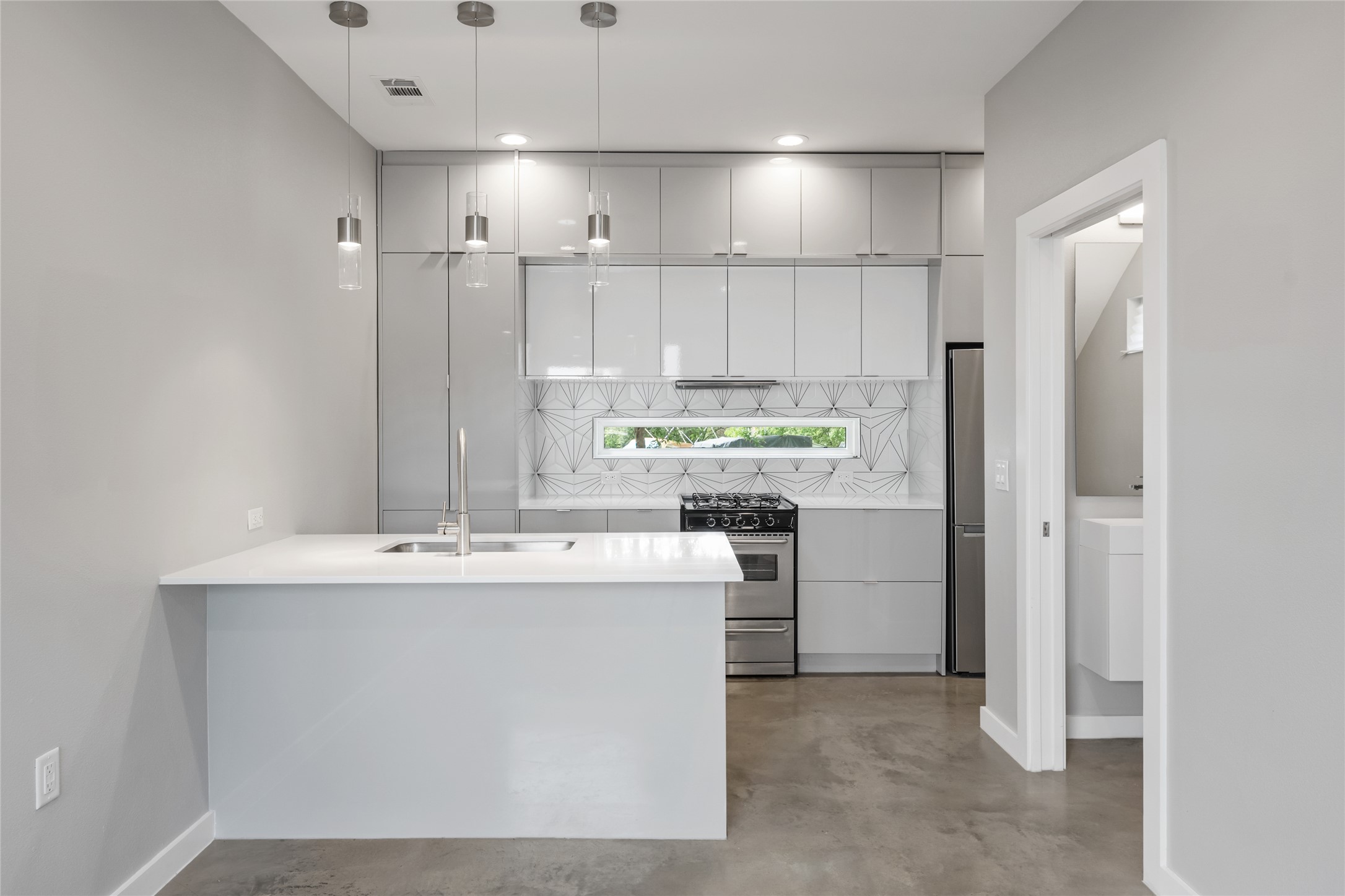 2108 Tillery Street, Unit 16 Austin, TX 78723 - Photo 3 of 15 Contemporary kitchen featuring white flat-panel cabinetry, a stainless steel range, and a geometric tile backsplash