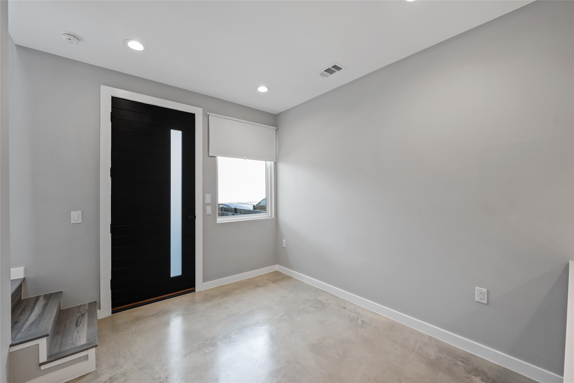 2108 Tillery Street, Unit 16 Austin, TX 78723 - Photo 6 of 15 Entryway featuring a modern black door with vertical glass insert, light gray walls, recessed lighting, and polished concrete flooring