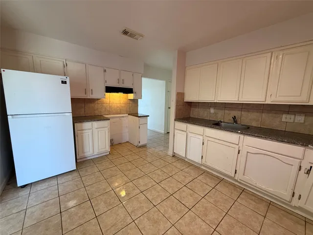 a kitchen with granite countertop white cabinets and refrigerator
