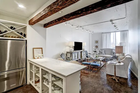 a living room with stainless steel appliances kitchen island granite countertop a table chairs a refrigerator and a stove