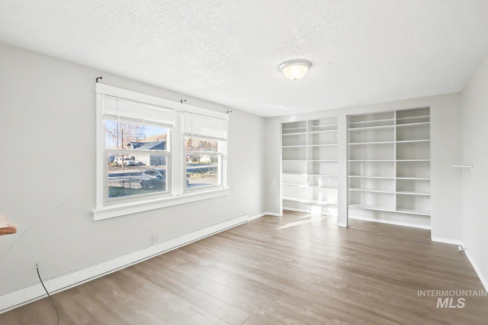 1830 Columbia Street Pomeroy, WA 99347 - Photo 16 of 28 Unfurnished room with a baseboard radiator, a textured ceiling, and wood finished floors